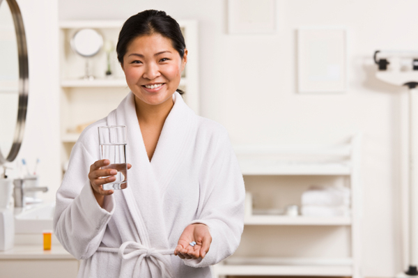 Woman taking medicine in bathroom