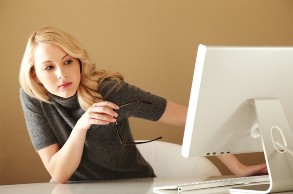 Woman peering around computer