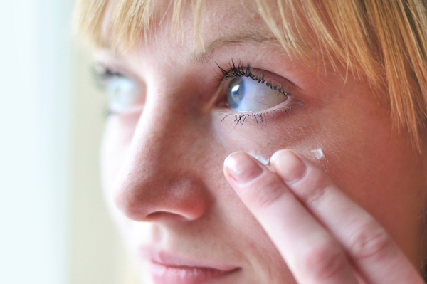 Woman applying under eye cream to hide dark circles