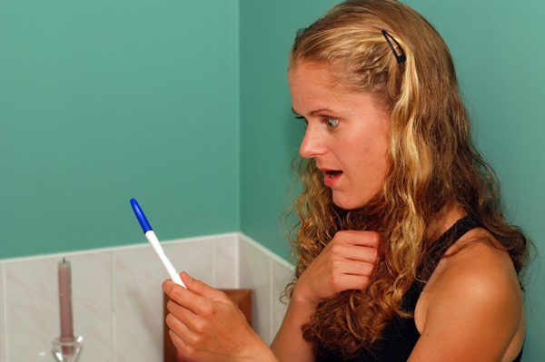 Shocked woman with pregnancy test
