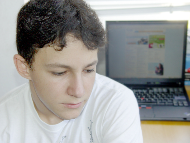 Teen facing away from laptop
