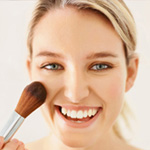 Woman applying blush to her cheeks
