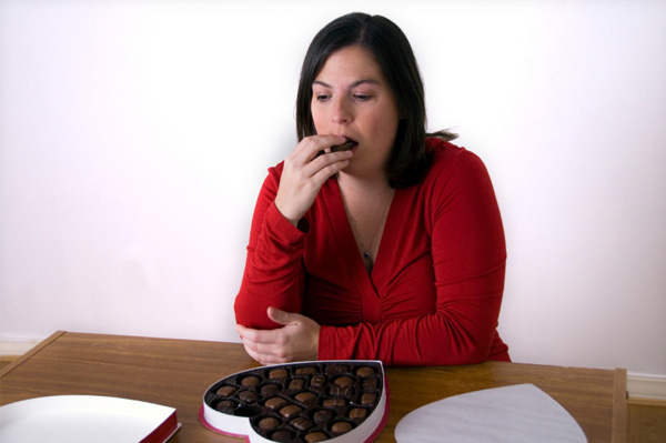 Sad woman eating chocolate