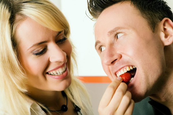 Woman feeding man strawberry