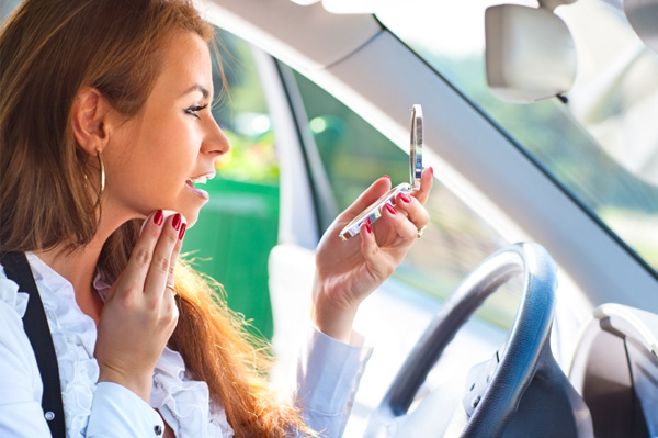Woman applying makeup in car