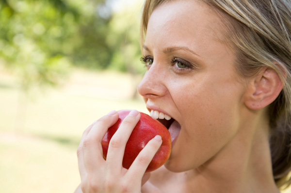 Woman eating apple outdoors