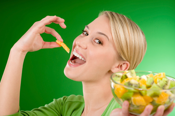 Woman eating oranges and kiwi