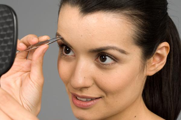 Woman tweezing brows