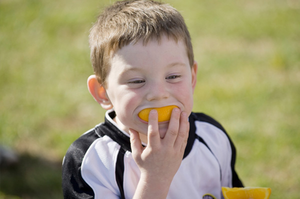 Athlete child eating orange