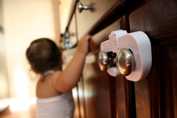 toddler walking along cabinet with doors safely latched