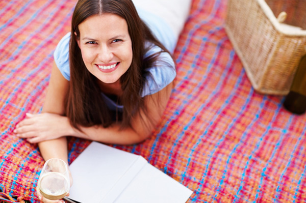 Woman reading book outside with wine