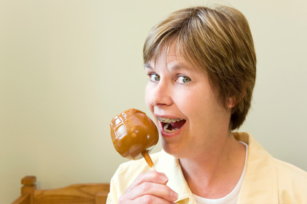 Woman with braces eating candy apple