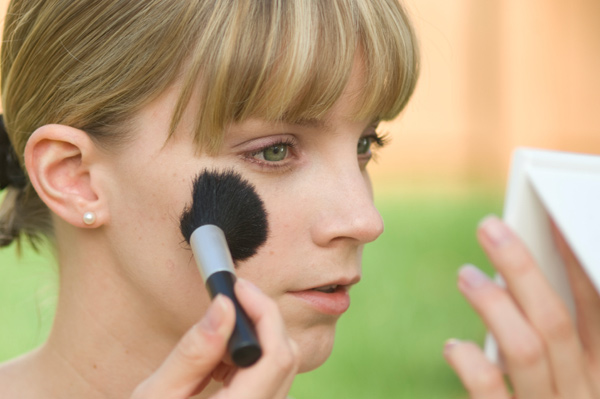 Woman with green eyes applying blush