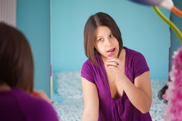 Teen girl applying lip gloss