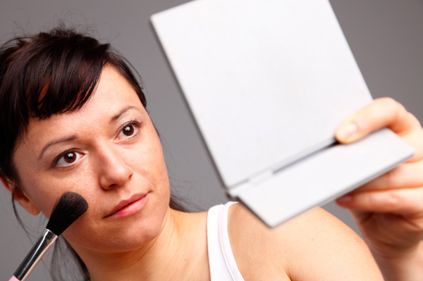Woman with black hair applying blush