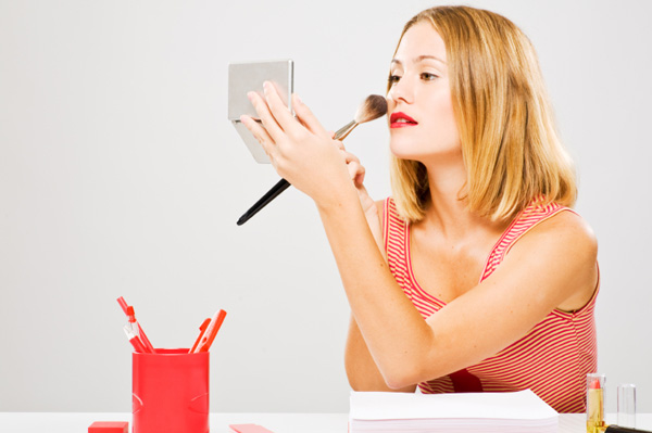 Woman applying makeup in office