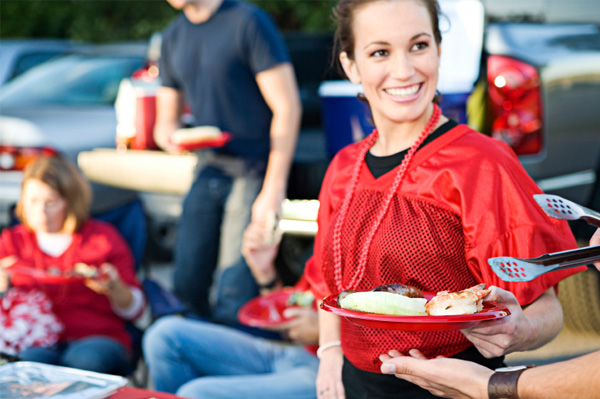 Woman getting hamburger from tailgate