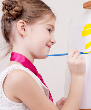 Little girl painting on easel