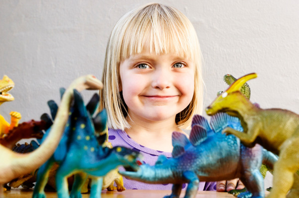 Little girl playing with toy dinosaurs