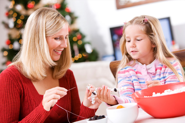 Mom making popcorn garland with daughter