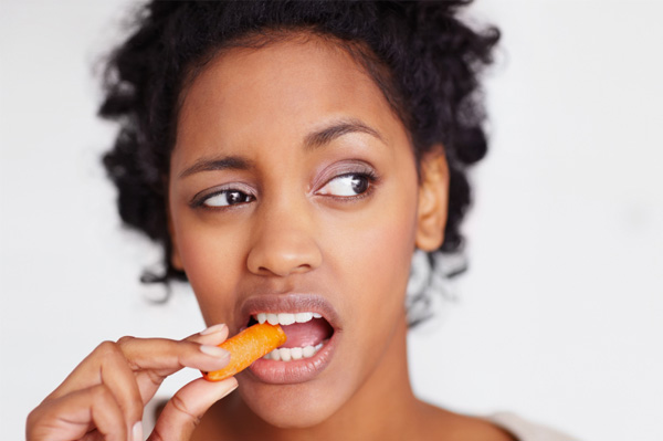 Unhappy woman eating a carrot