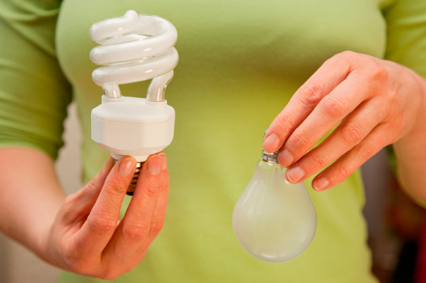 woman switching out old lightbulbs with new cfl