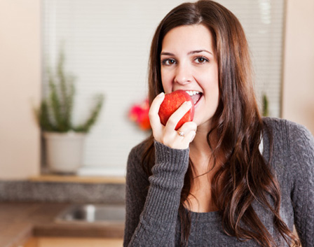 Woman eating apple in kitchen