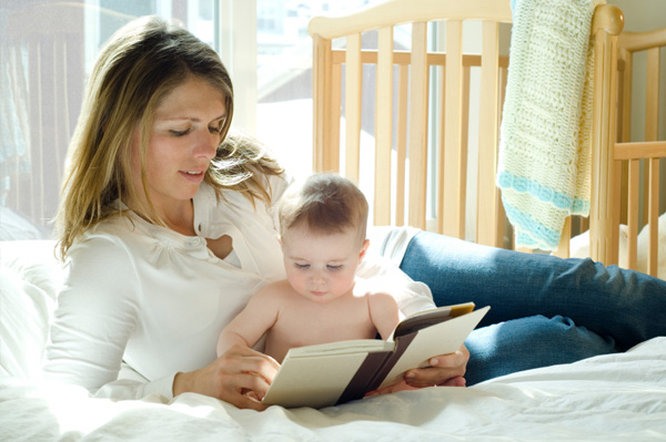 mom reading to baby in bed