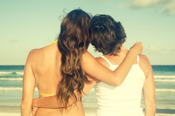 Grown daughter and mother standing together by beach