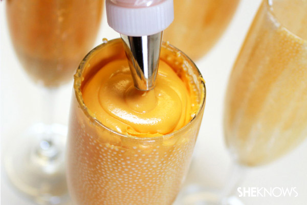 Piping frosting on the second cupcake in the glass