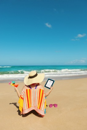 woman relaxing on beach with an ereader