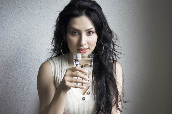 Woman with headache drinking water