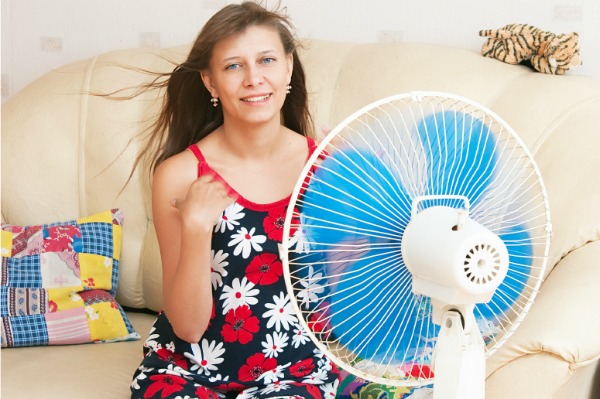 girl cooling off by sitting next ot an oscillating fan