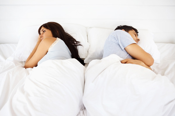 Couple laying back to back in bed
