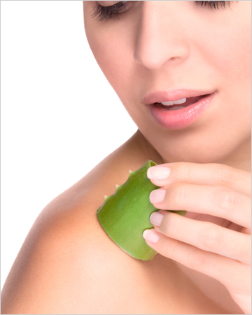 Woman applying aloe vera gel to skkin