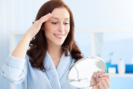 Woman looking at eyebrows in mirror