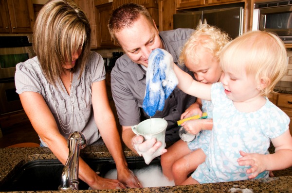 family washing dishes together in modern kitchen