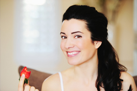 Happy woman eating strawberry