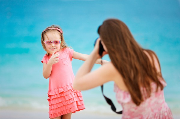 mother photographing daughter on beach vacation