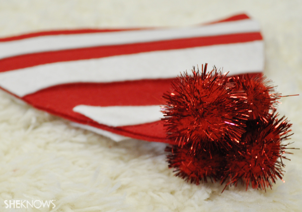 Glue the red puff balls onto the top of Waldo's hat to complete it
