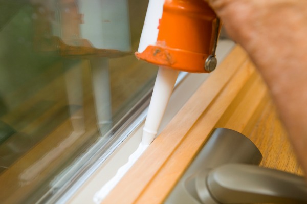 man caulking window sills