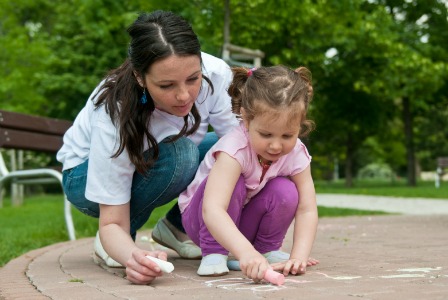 mom doing sidewalk chalk with child