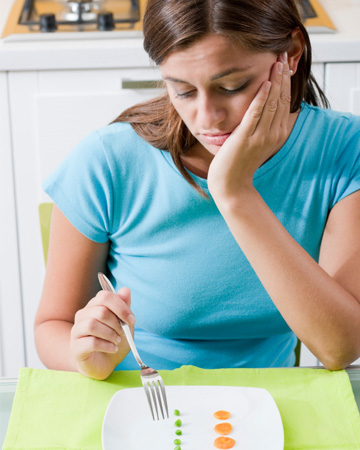 Woman eating pea and carrot