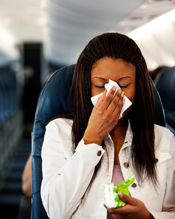 Woman sneezing on plane