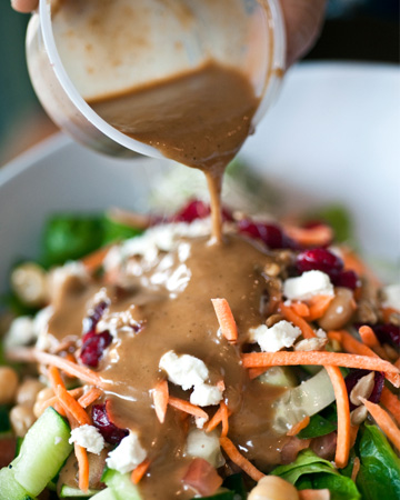 Woman pouring salad dressing