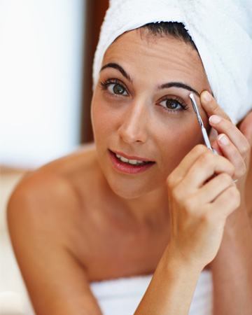 Woman tweezing eyebrows