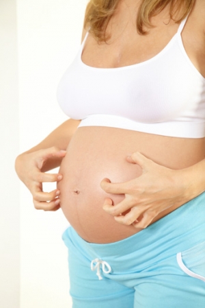 Pregnant woman itching her belly