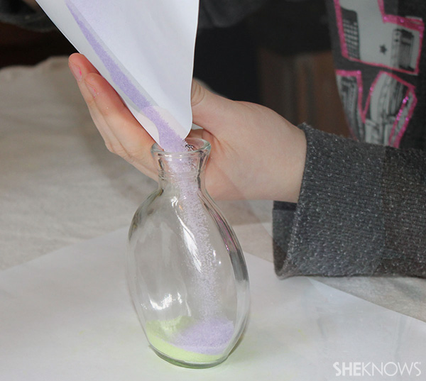 funneling colored salt into jar