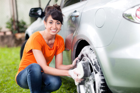 Smiling woman washing car