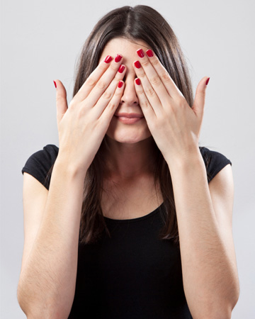 Woman hiding behind hands